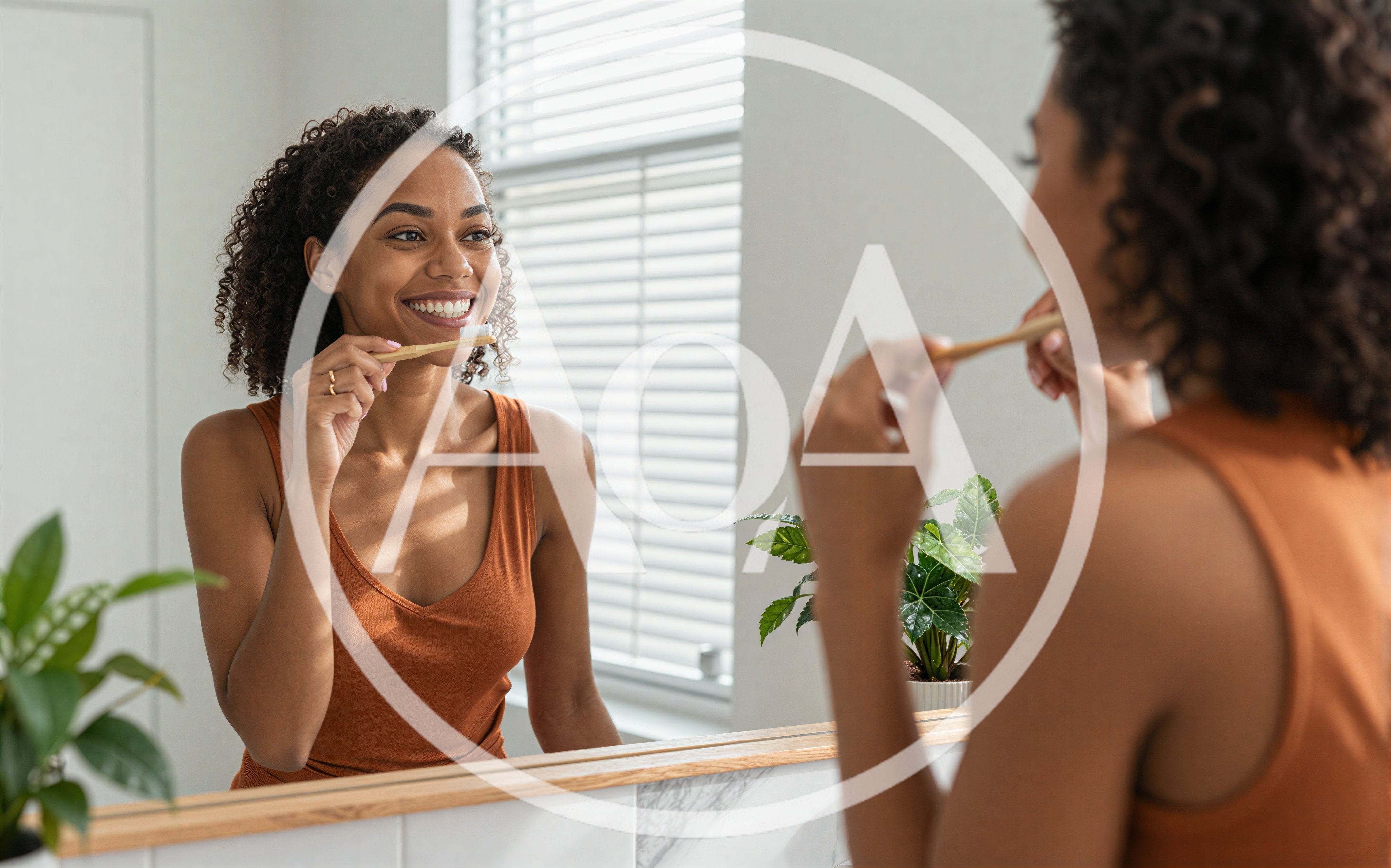 Young Woman Brushing Teeth In Front Of Bathroom Mirror