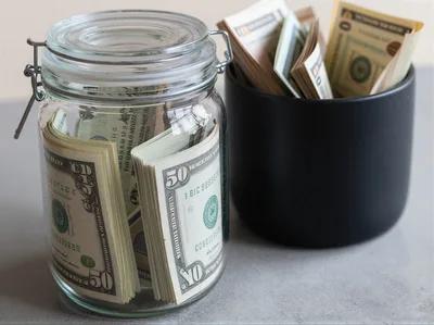 Stacks Of Fifty Dollar Bills In Glass And Ceramic Jars