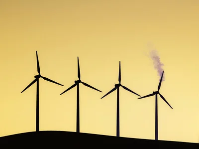 Four Wind Turbines Silhouetted Against A Golden Sunset