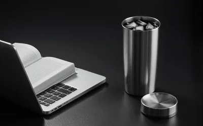 Open Book On Laptop With Metal Tumbler
