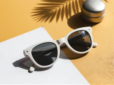White Sunglasses And Silver Container On Yellow Background