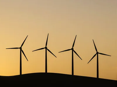 Four Wind Turbines Silhouetted Against A Golden Sunset