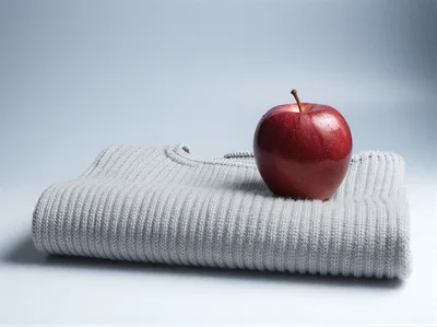 Red Apple Resting On A Folded Grey Sweater