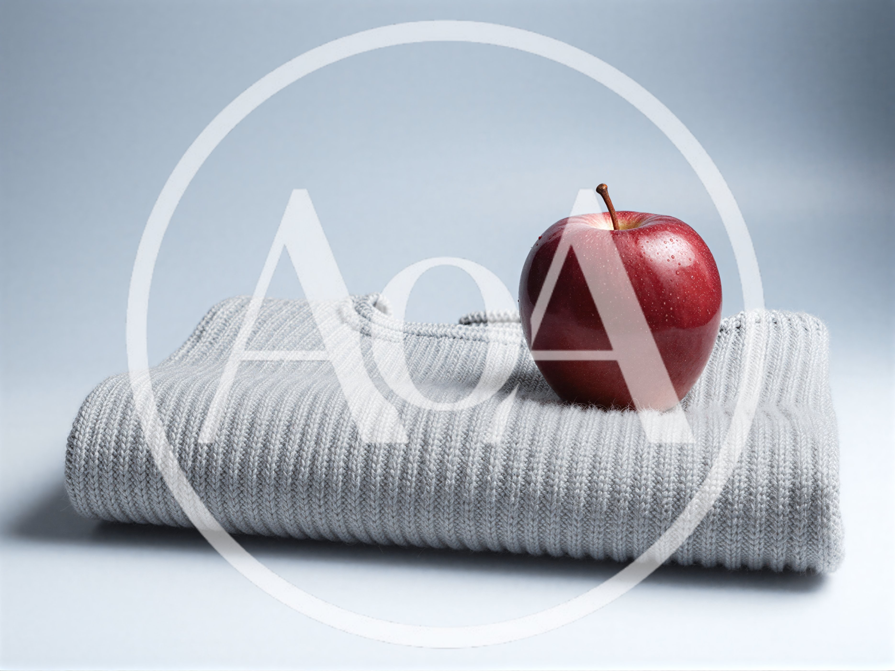 Red Apple Resting On A Folded Grey Sweater