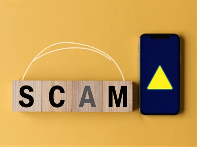 Wooden Blocks Spelling Scam Next To Smartphone With Warning Icon