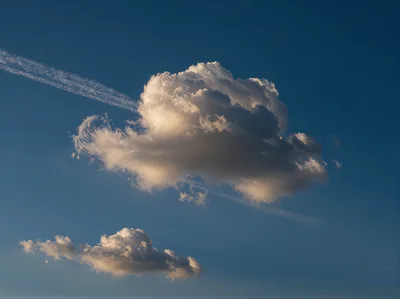 Cumulus Cloud With Airplane Contrail In Blue Sky
