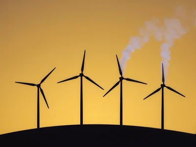Wind Turbines Emitting Smoke Against A Golden Sunset