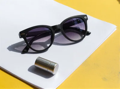Black Sunglasses And Metal Object On White Paper