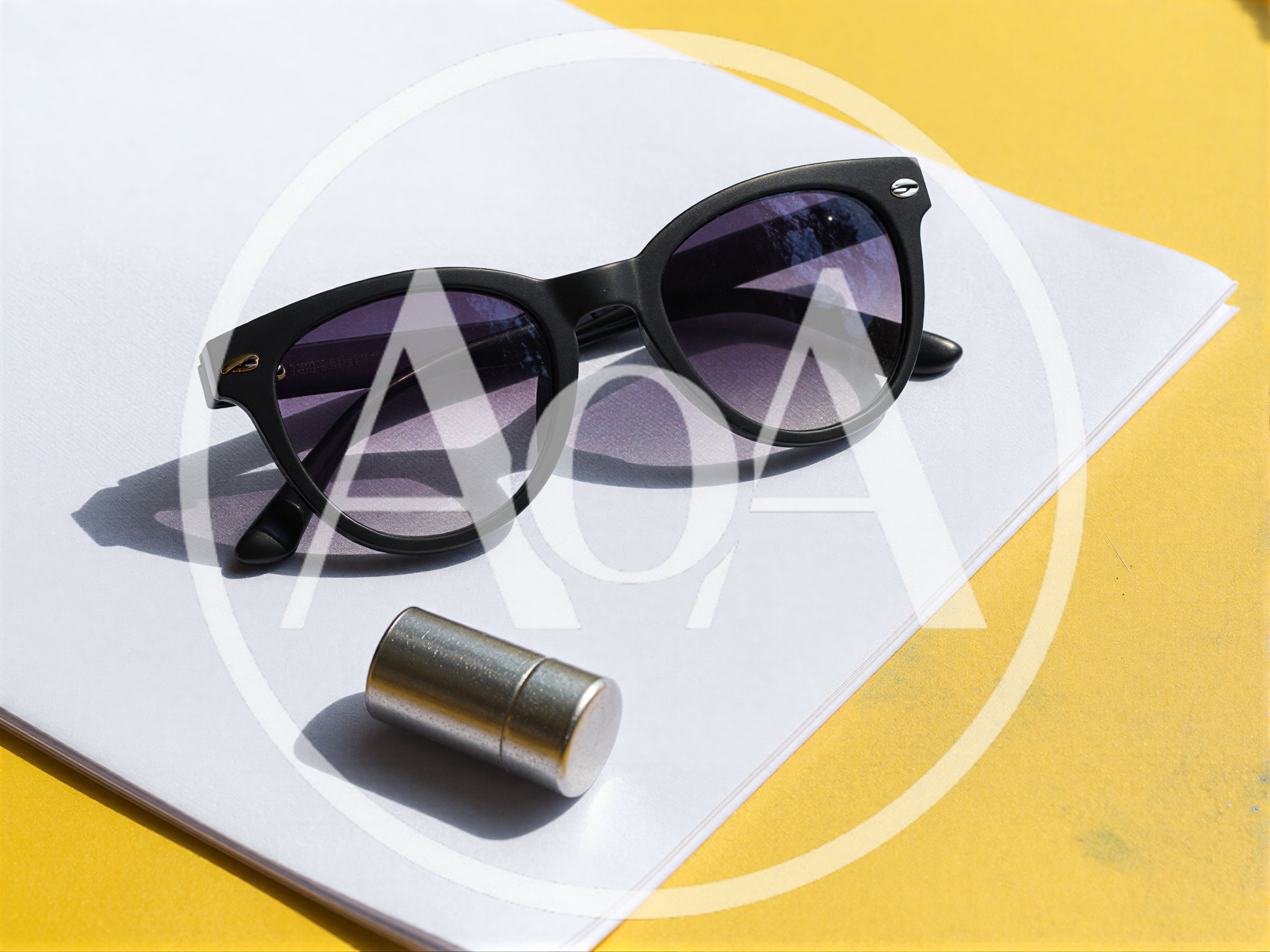Black Sunglasses And Metal Object On White Paper