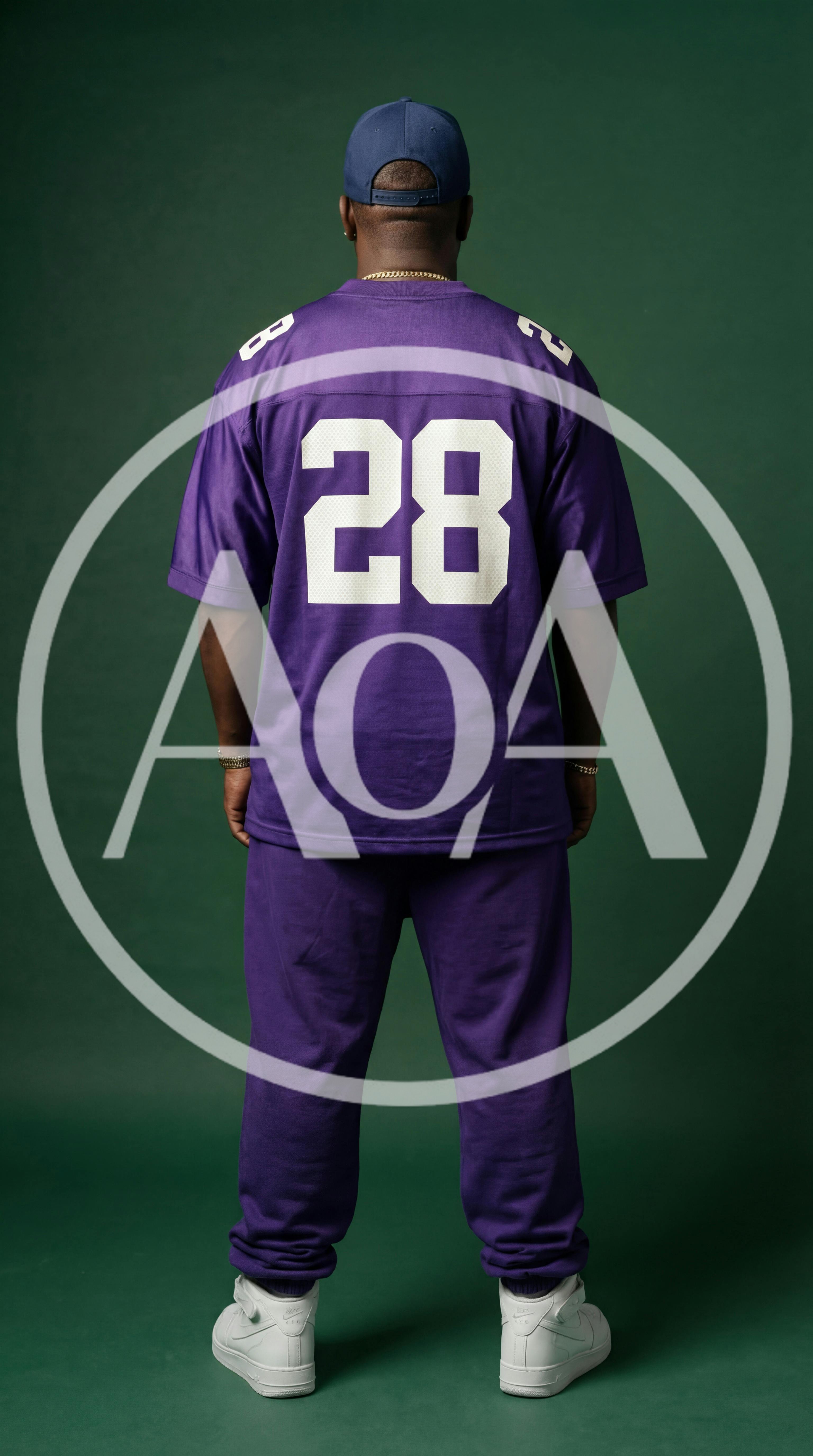 Man Wearing Purple Sports Jersey Standing Against Green Background
