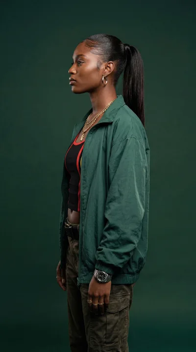 Young Black Woman Standing In Profile Against Green Background