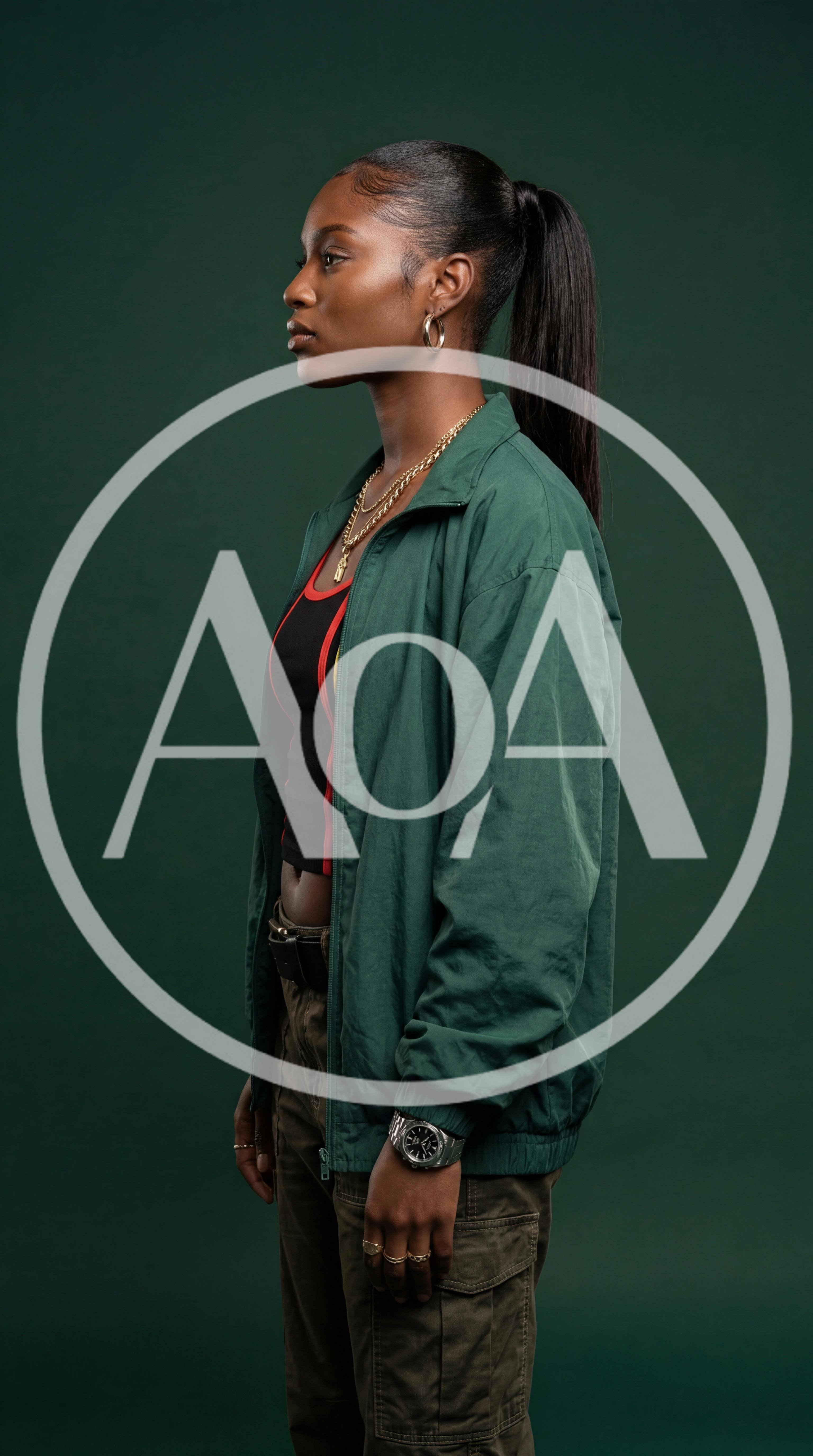 Young Black Woman Standing In Profile Against Green Background