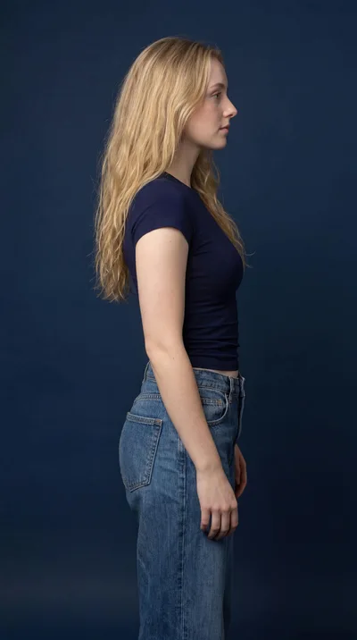 Side Profile Of A Young Woman Standing Against Blue
