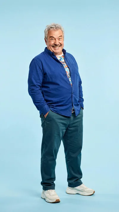 Smiling Mature Man Standing Against Blue Background
