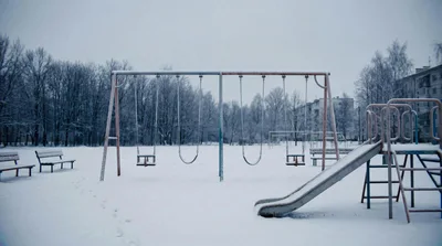 Empty Playground Swings In A Snowy Winter Park