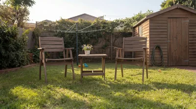Two Wooden Garden Chairs And Table On Lawn