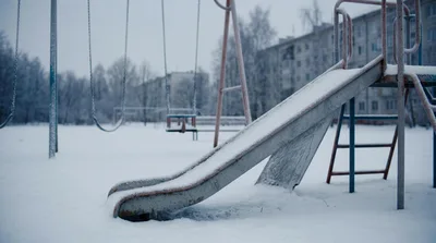 Empty Playground Slide and Swings in Snowy Winter
