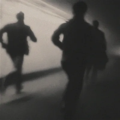 Silhouetted Figures Running Through A Dark Tunnel