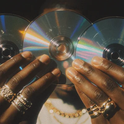 Man Holding Three Reflective Compact Discs Towards Camera