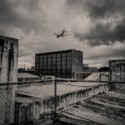 Commercial Airplane Flying Over Urban Rooftop In Cloudy Weather