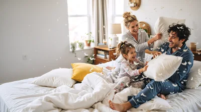 Happy Family Having A Fun Pillow Fight In Bedroom