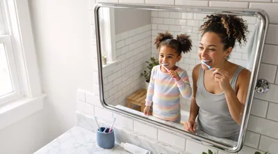 Mother and Daughter Brushing Teeth Together in Bathroom