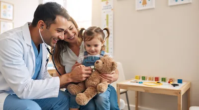 Pediatrician Examining A Young Girl And Her Teddy Bear