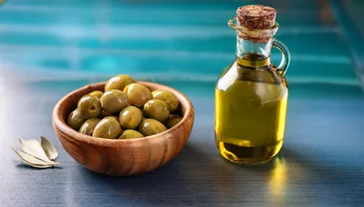 Green Olives In Wooden Bowl With Olive Oil Bottle