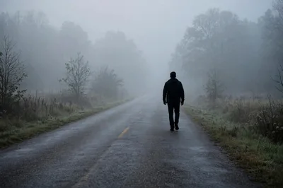 Man Walking Alone Down A Foggy Country Road