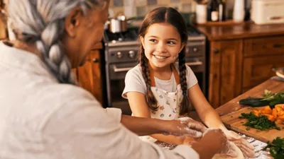 Grandmother and Granddaughter Kneading Dough in Kitchen