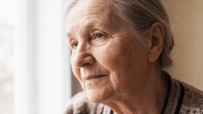 Elderly Woman Looking Out Window Thoughtfully