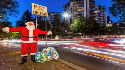 Santa Claus Standing With Christmas Sign And Trash Bags