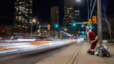 Santa Claus Standing On A Busy City Street At Night