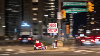 Santa Claus Kneeling on City Street at Night