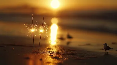 Two Burning Sparklers on a Sandy Beach at Sunset