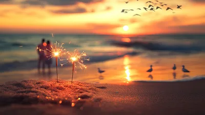 Two Sparklers Burning On A Beach At Sunset