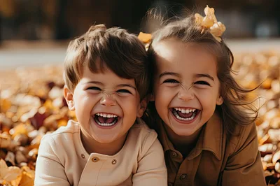 Two Happy Children Laughing Together In Autumn Leaves