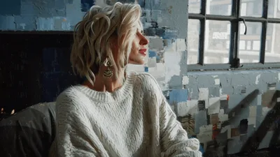 Blonde Woman Sitting In Artistic Studio Looking Out Window