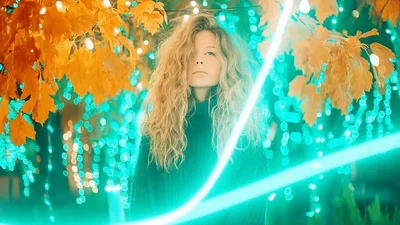 Young Woman With Curly Hair Surrounded By Neon Light Trails