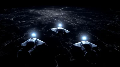 Three Wingsuit Flyers Gliding Over Illuminated City At Night