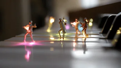 Miniature Figurines Dancing On A Piano Keyboard