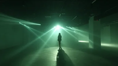 Woman Walking Towards Bright Green Stage Lights