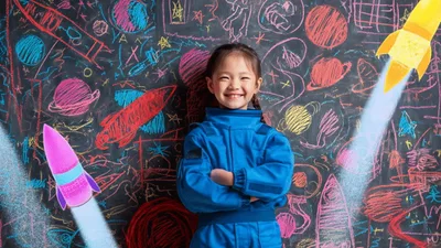 Little Girl In Astronaut Costume Standing Before Space Chalkboard