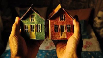 Hands Holding Two Miniature Paper Houses