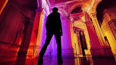 Man Standing In Ornate Hallway With Dramatic Lighting
