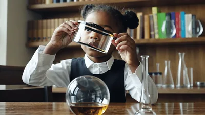 Young Girl Examining Liquid In Laboratory Glassware