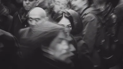Young Woman Standing Still Amidst A Moving Crowd