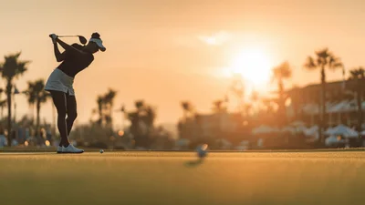 Female Golfer Swinging Club During Golden Hour