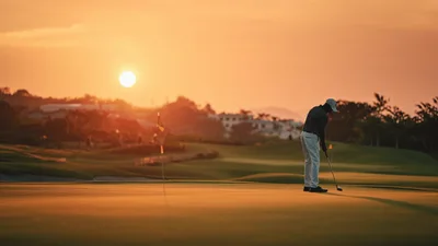 Golfer Putting On Green During Golden Hour Sunset