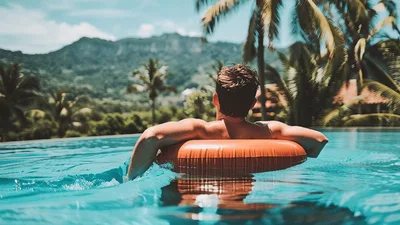 Man Relaxing On Inflatable Ring In Tropical Infinity Pool